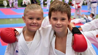Die Karate-Talente Rani Wienbeck und Asim Malsagov umarmen sich und lächeln.