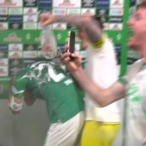 Werder-Kapitän Ömer Toprak bekommt während eines Interviews von Mitspielern eine Bierdusche verpasst.