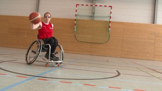 Die Rollstuhl-Basketballerin Jana Bozek prellt fahrend mit einem Ball.