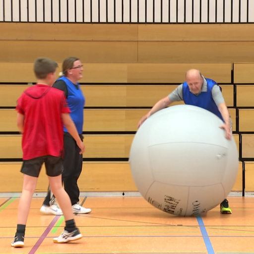 Menschen spielen mit einem großen Ball in einer Halle