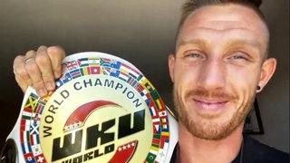 Der Kickboxer Pascal Schroth zeigt seinen WM-Titel und lächelt in die Kamera.