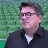 Werder-Präsident Hubertus Hess-Grunewald gibt im Innenraum des Weser-Stadions vor den grünen Sitzreihen ein Interview.