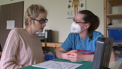 Jill Geffken (links) löst mit einer Pflegerin ein Kreuzworträtsel
