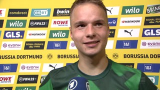 Werder-Joker Niklas Schmidt lächelnd vor einer Werbewand nach dem Sieg in Dortmund beim Interview.