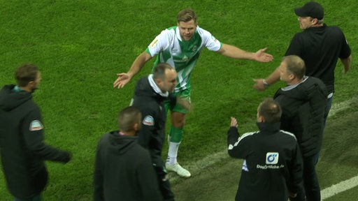 Werder-Stürmer Niclas Füllkrug echauffiert sich mit Trainer Ole Werner gestikulierend an der Seitenlinie über den Vierten Schiedsrichter.