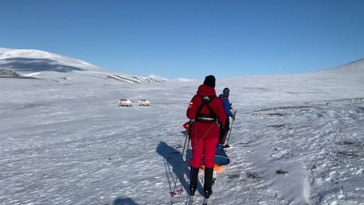 Eine schneebedeckte Landschaft mit zweit Menschen mit Skiern.