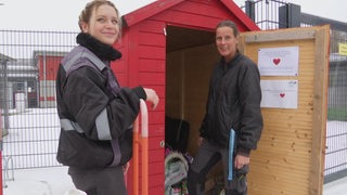 Zwei Frauen öffnen eine Spendenbox.