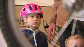 Der 4-jährige Kalle schaut bei der Reparatur seines Fahrrads zu