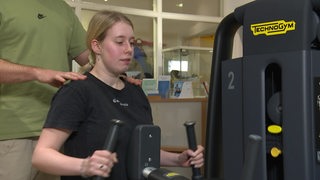 Eine Frau sitzt an einem Fitnessgerät 