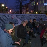 Demonstranten sitzen vor dem Bremer Theater bei Nacht