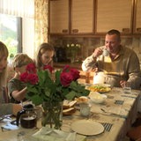 Ukrainischer Soldat sitzt mit seiner Frau und Kindern am Tisch und frühstückt