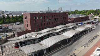Ein Gebäude, das neue Polizeikommissariat West, steht hinter einer großen Bahnhaltestelle.