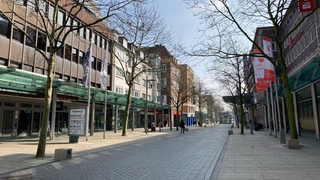 Blick in eine leere Straße. Links und rechts sind Läden.