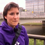 Eine Frau mit kurzen braunen Haaren und lila Pulli steht vor der Kamera.