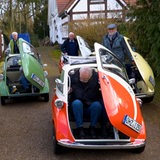 Männer steigen aus mehreren Isetta-Oldtimern in verschiedenen Farben aus