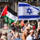 Menschen halten eine israelische und eine palästinensische Flagge auf dem Bremer Marktplatz hoch.