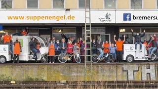 Das Team der Suppenengel Bremen posiert am Gleis mit speziellen Lastenrädern