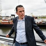Ein Mann im Jacket steht vor einem Hafenbecken.