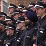 Menschen in Polizeiuniform stehen nebeneinander. Ein Feuerwehrmann trägt einen Turban