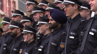 Menschen in Polizeiuniform stehen nebeneinander. Ein Feuerwehrmann trägt einen Turban