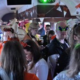Verkleidete Menschen feiern in einem Zugabteil
