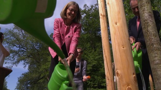 Die Botschafterin des Vereinigten Königreich Jill Gallard gießt einen Eichelbaum im Bürgerpark. 