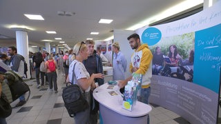Passanten informieren sich an einem Stand der Jobmesse in Bremen.