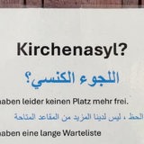 Ein Schild mit Text hängt an einer Holztür.