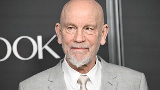 John Malkovich schaut bei einer Premierenfeier in die Kamera. 