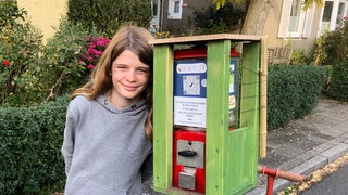 ein Junge lehnt an einem umfunktinierten Kaugummiautomaten