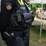 Polizeischutz bei einer Veranstaltung der Jüdischen Gemeinde im Land Bremen. Im Vordergrund sind zwei Polizisten zu sehen und im Hintergrund Menschen, die draußen unter Zelten an langen Tischen essen. 