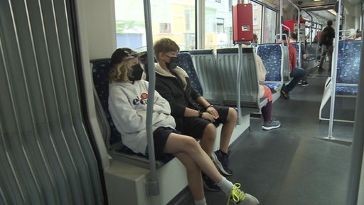 Zwei Jugendliche sitzen in einer Straßenbahn der Bsag und fahren durch Bremen. 