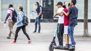 Kinder fahren zu dritt auf einem E-Scooter