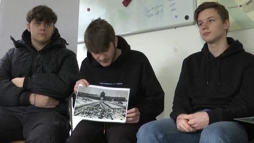 Jugendliche im Interview. Ein Jugendlicher hält ein Foto vom Auschwitzer Konzentrationslager in den Händen.