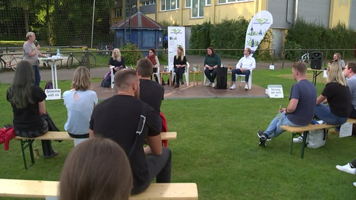 Auf einer Grünfläche sitzen zukünftige WählerInnen zu einem Gespräch gegenüber den Kandidatinnen der Bundestagswahl.
