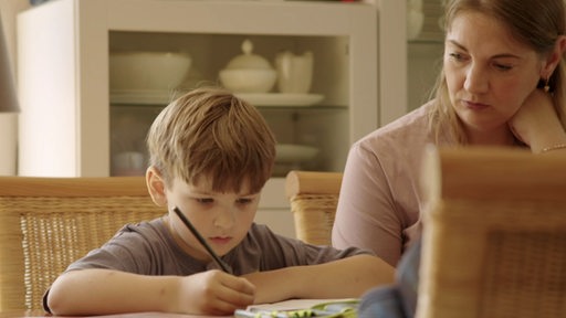 Ein Junge lernt zuhause mit seiner Mutter.