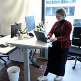Eine junge Frau steht an ihrem Arbeitsplatz.