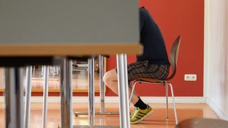 Ein junger Wähler in kurzer Hose und T-Shirt sitzt bei der Stimmabgabe in einer Wahlkabine (Archivbild)