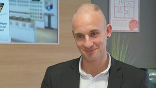 Zu sehen ist Kevin Grobbin beim Interview in seinem Handyladen.