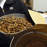 Ein Mann füllt beim Bremer Cross Coffee in der Rösterei Bohnen in eine Verpackung.