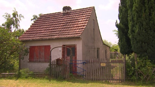 Ein kleines, altes Kaisenhaus mit einem Zaun davor.