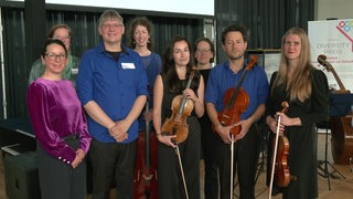 Musiker des Kammerensembles Konsonanz schauen in  die Kamera, ihre Instrumente in der Hand.