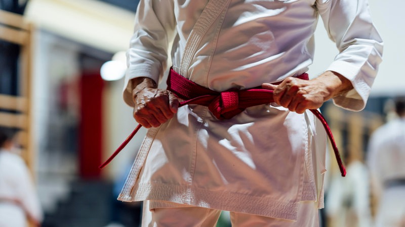 Ein Mann bindet seinen roten Karate-Gürtel