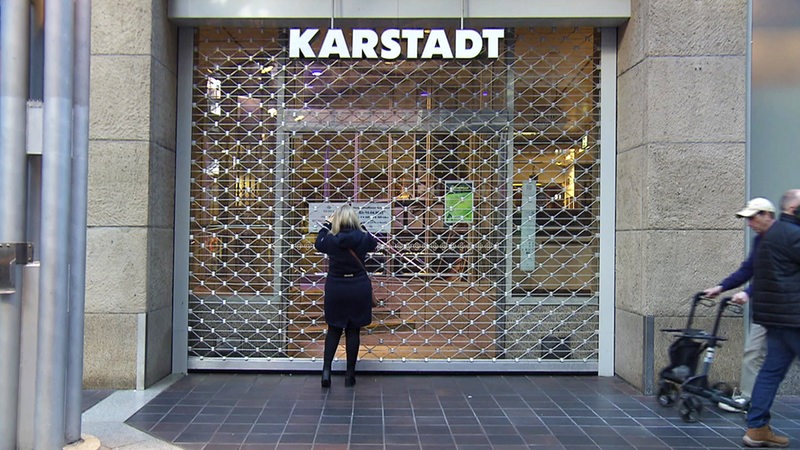 Geschlossene Karstadtfiliale in Bremen am 13.3.2023. Die Gitter sind heruntergelassen, eine Frau steht davor.
