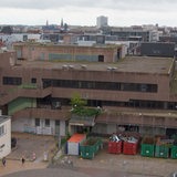Blick auf ein braunes Gebäude. Davor stehen Container.