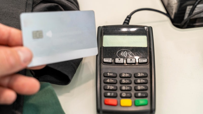 Eine Person bezahlt mit einer Karte an einem Terminal.
