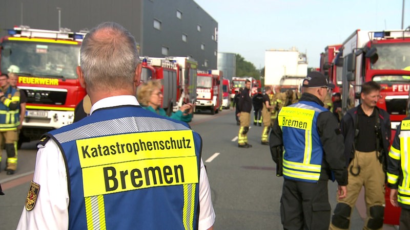 Ein Mann in Warnweste auf der Katastrophenschutz Bremen steht steht vor einer Reihe Feuerwehrautos.