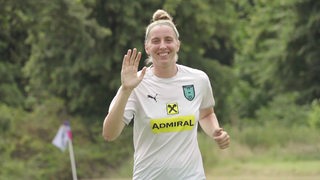 Werder-Spielerin Katharina Schiechtl winkt beim Laufen im Training fröhlich in die Kamera.