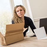 Eine Frau sitzt  vor einem Laptop und bezahlt eine Rechnung für eine Lieferung (Symbolbild)