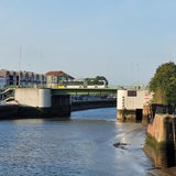Ein Bus fährt über eine Brücke, die über einen Fluss führt.
